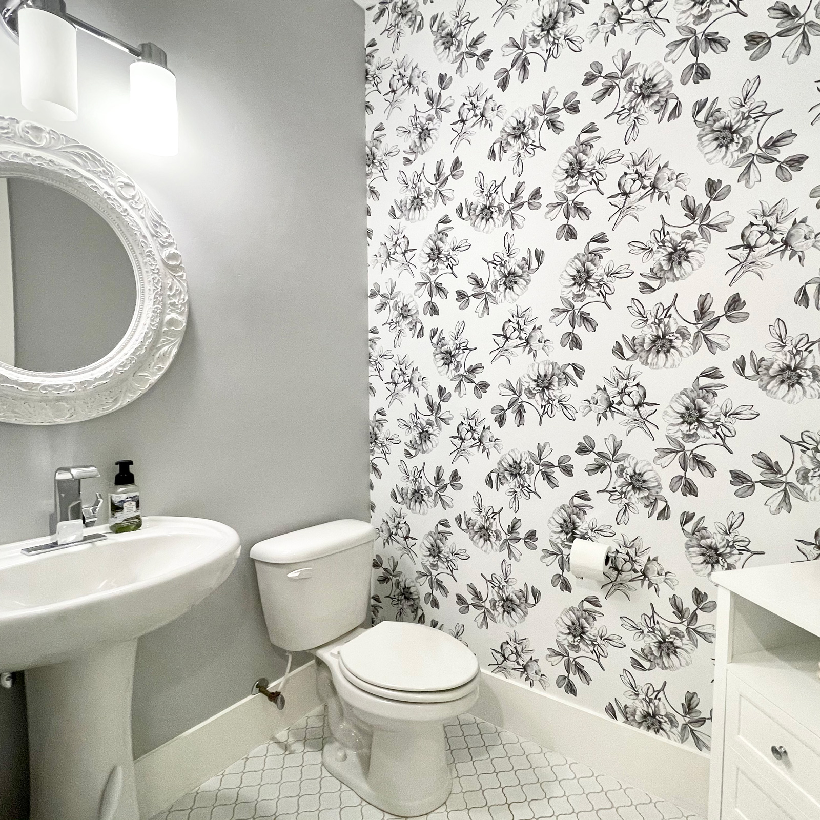 Modern bathroom with floral wallpaper and white fixtures.