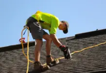 Worker in safety gear repairing roof.